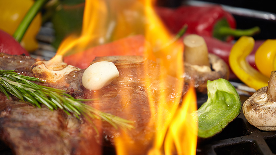 Steak and vegetables cook on a grill