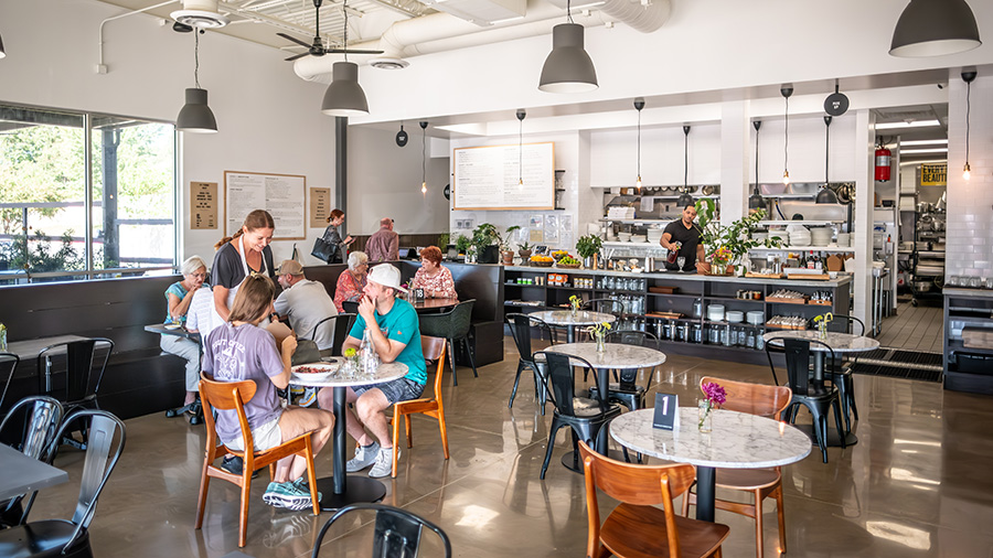 An industrial style restaurant dining room at James Provisions with customers enjoying lunch