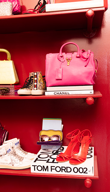 Boutique shoes, sunglasses and a handbag are arranged on a red shelf