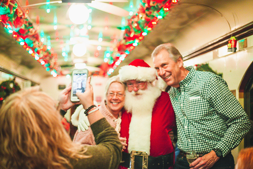 Santa poses for a photo with two adults