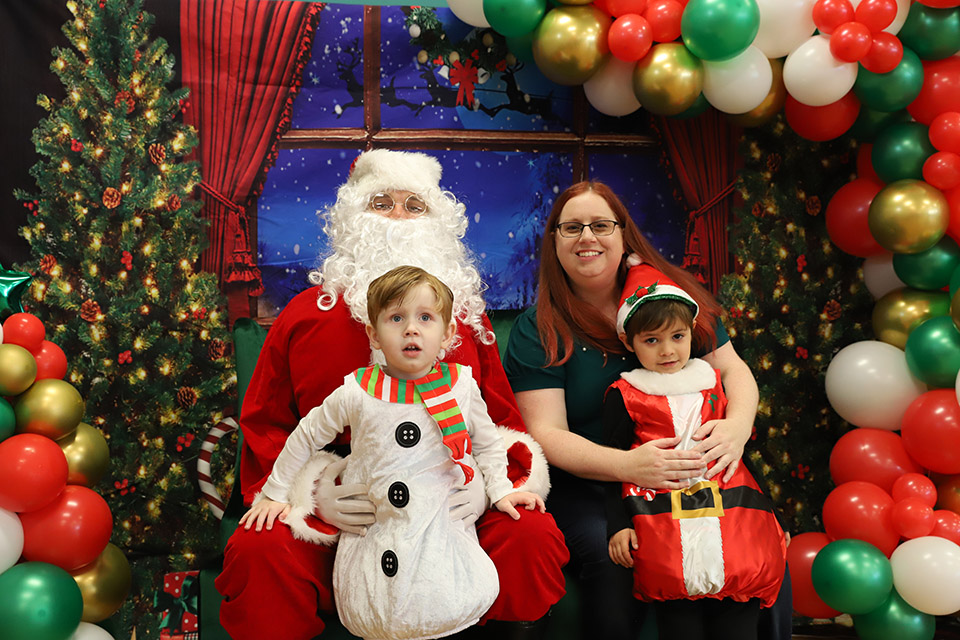 Santa poses with a woman and two children, dressed as a snowman and a tiny Santa Claus