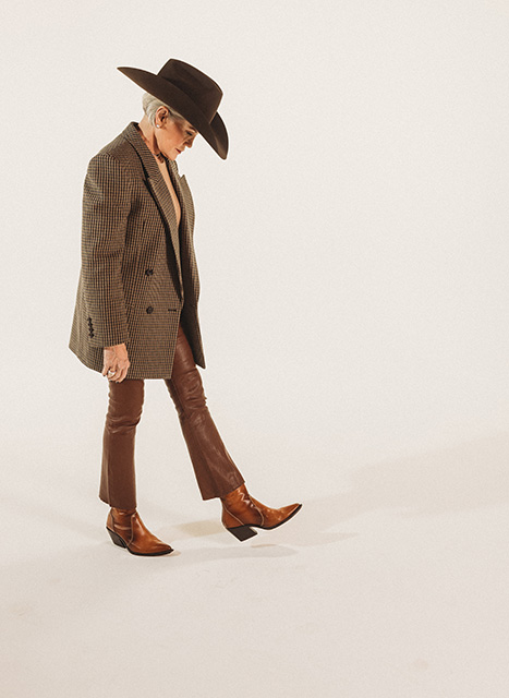 Susan Maddox sports her custom hat in a brown blazer, brown pants and brown Western boots.