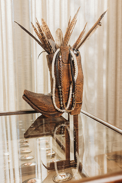 Jewelry hangs on a Western boot, with feathers