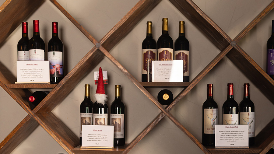 A variety of wines are arranged on a wood shelf