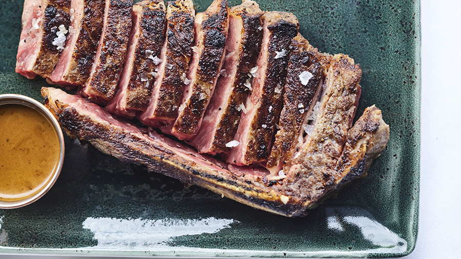 A sliced porterhouse steak with sauce from Al Biernatʻs