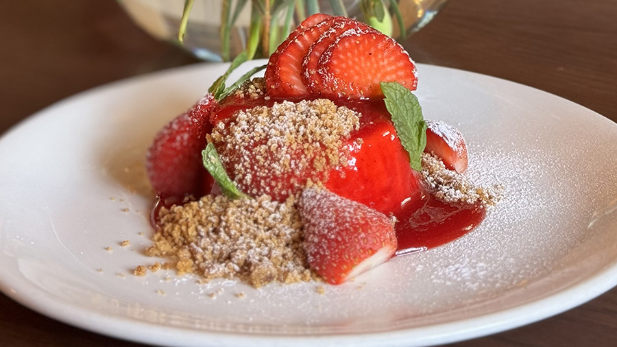 Cheesecake covered in strawberry sauce and topped with fresh strawberries