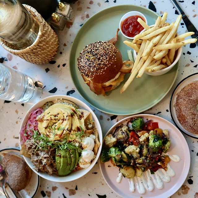 Three plates display a burger and fries, plus other offerings from Box St. All Day.