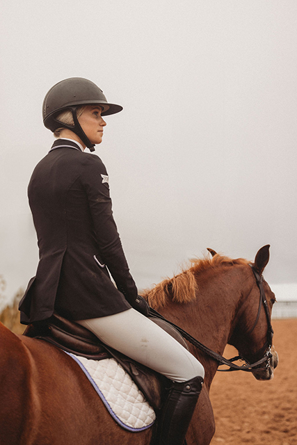 A student-athlete looks out on the horizon from her horse