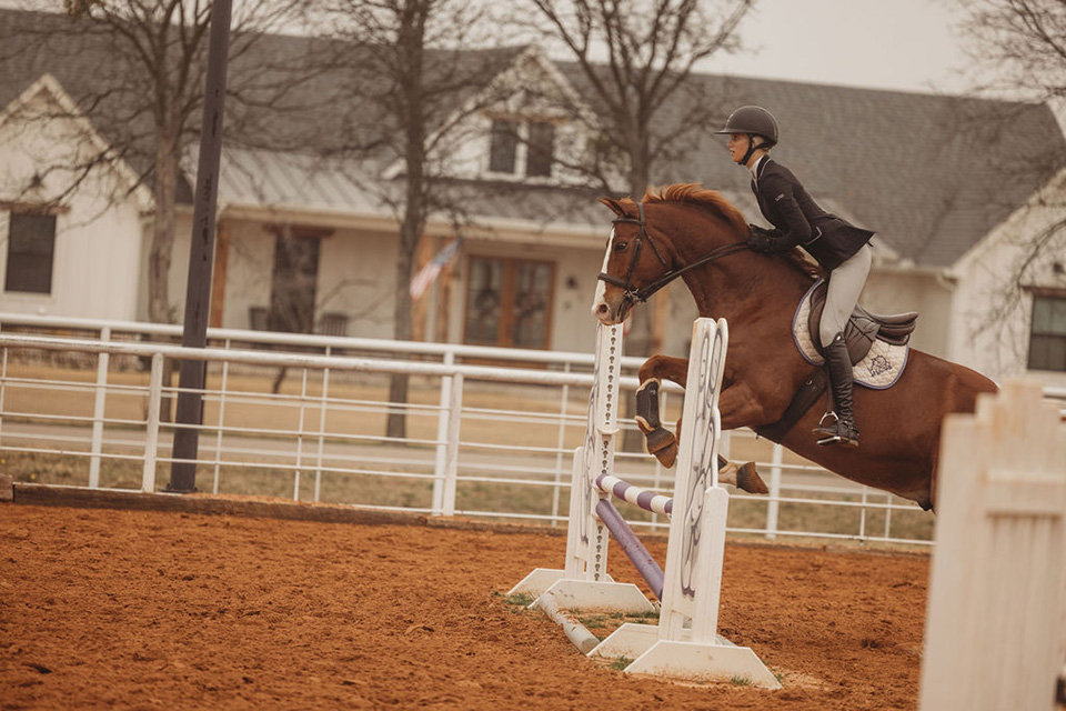 One of TCU equestrian's student-athletes and her horse are mid-jump.