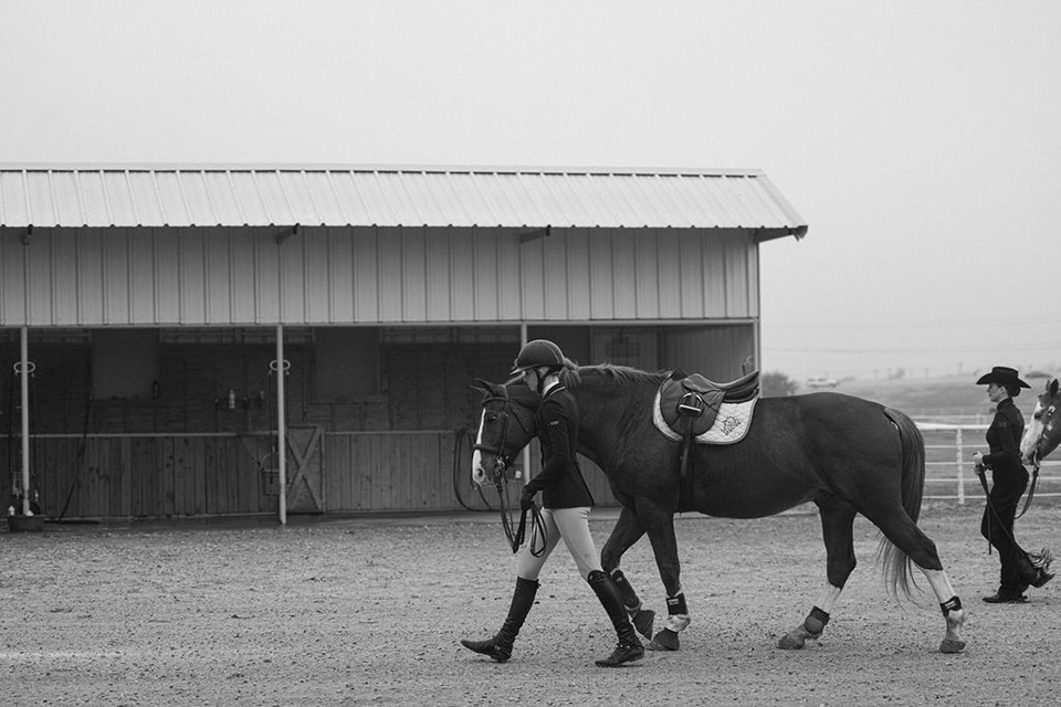 A student-athlete leads a horse.