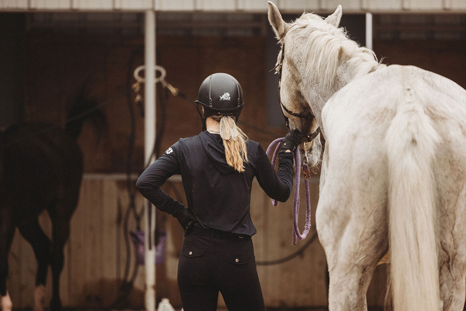 A student-athlete leads a horse.