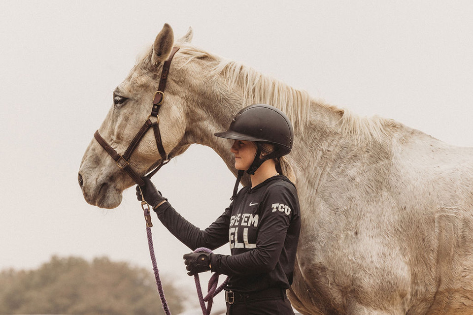 A TCU equestrian student-athlete guides her horse