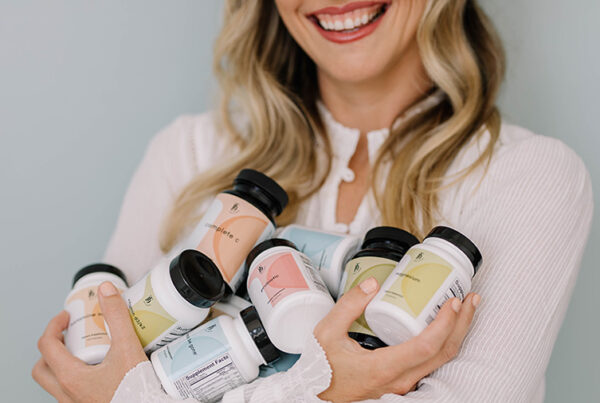 Taylor Dukes holds bottles from her line of wellness supplements