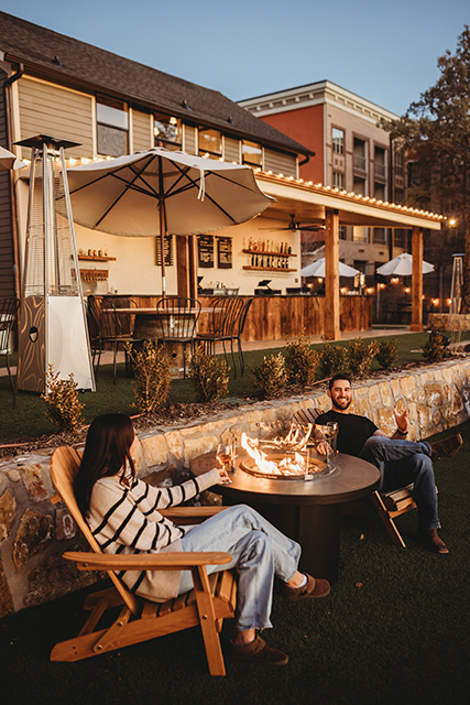 A couple enjoys the firepit and the view behind Saddlerock Wine + Beer